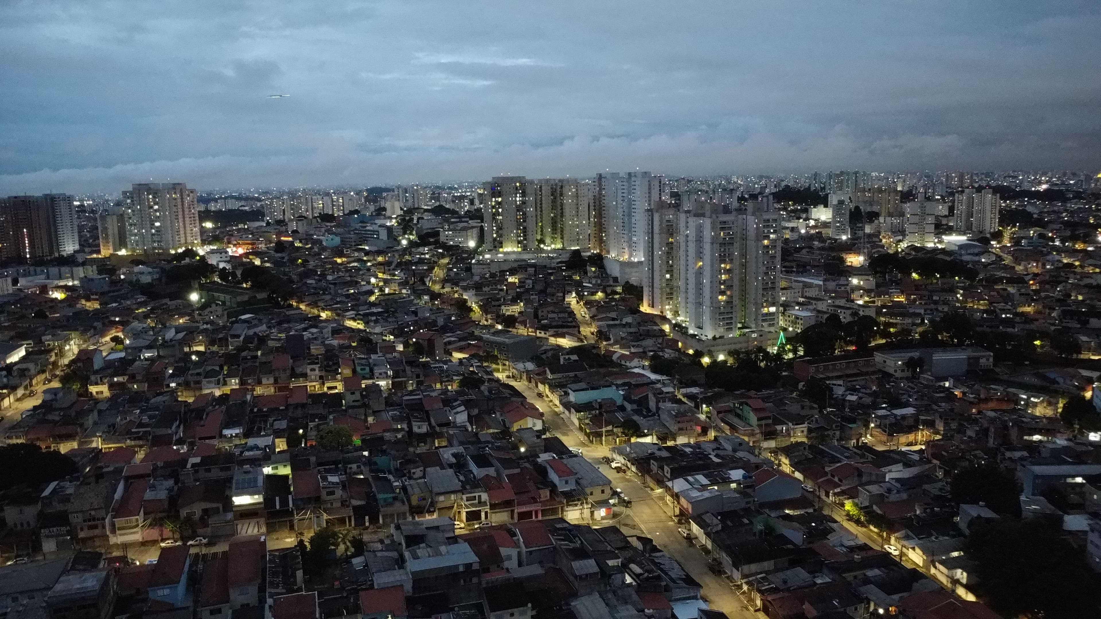 Panorama urbano ao anoitecer, com as luzes das ruas acesas